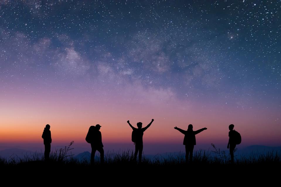 Silhouette group of young traveler and backpacker watched the star and milky way on top of the mountain with twilight sky. He enjoyed traveling and was successful when he reached the summit.