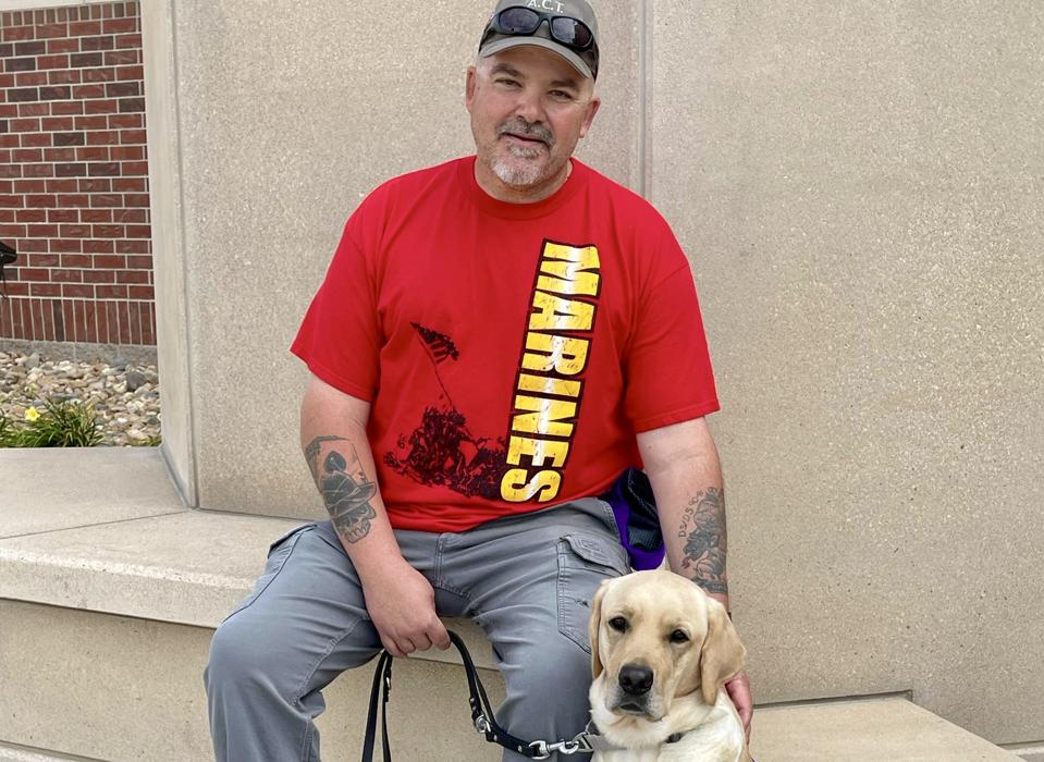 Hank Ford poses with his service dog Tommy, a yellow Labrador retriever from the nonprofit Dogs Inc.