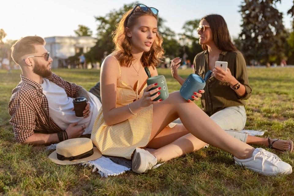 Frineds having fun in the park while listening to a couple of Tribit StormBox Mini Plus speakers