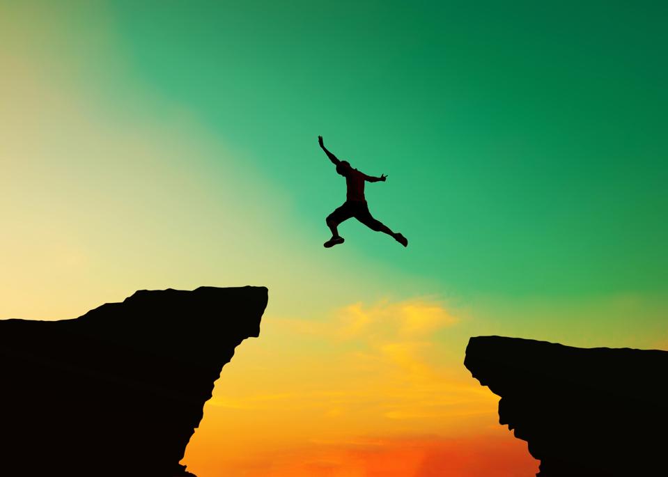 An image of a person leaping through the air, suspended in the gap between two cliffs, representative of thte small business technology gap