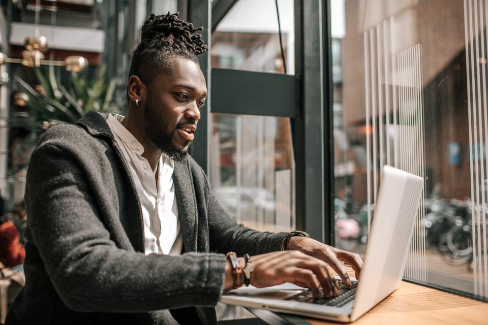 Handsome black adult student using AI A.I. on a laptop computer