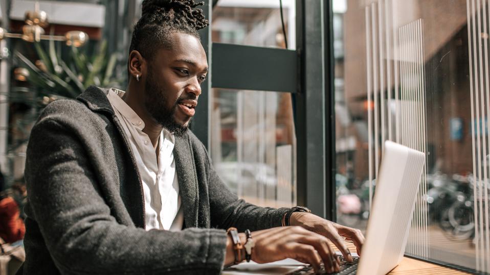 Handsome black adult student using AI A.I. on a laptop computer