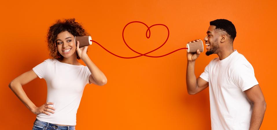 Young black couple with can phone on orange background