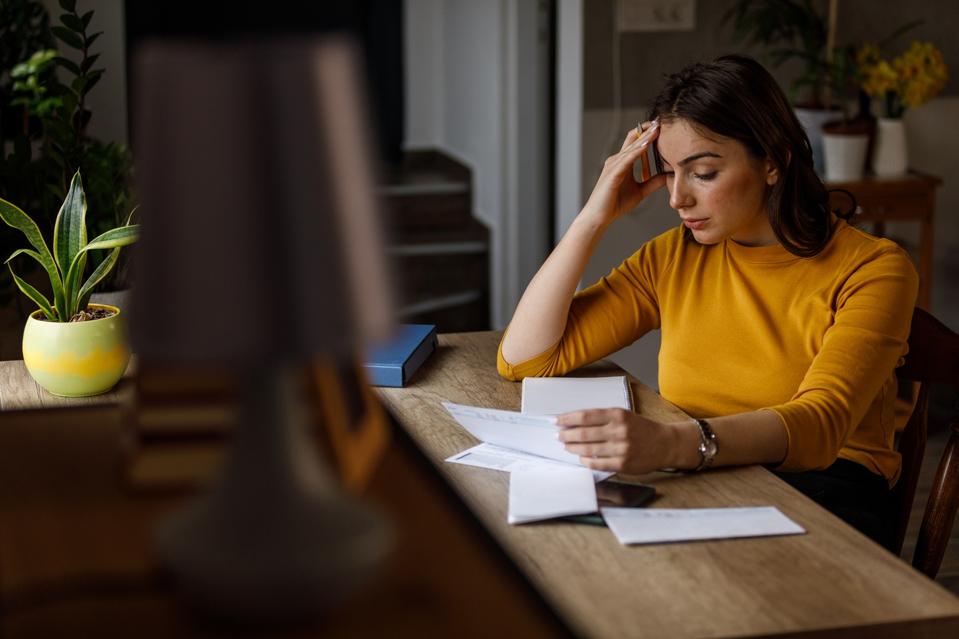 Young woman sorting out her monthly bills and struggling with finances
