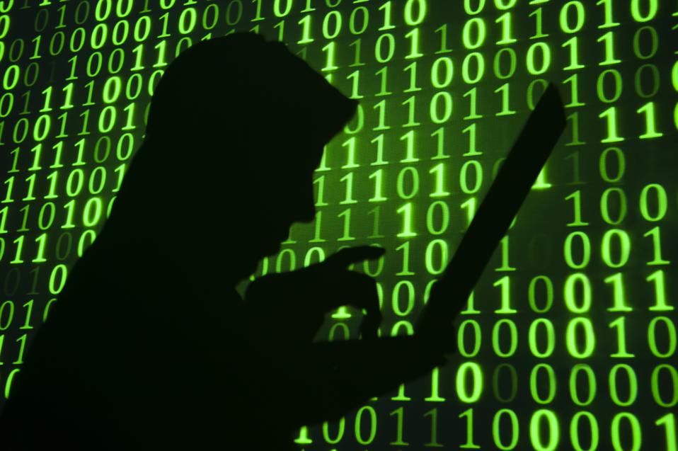 Computer hacker silhouette with green binary code background 