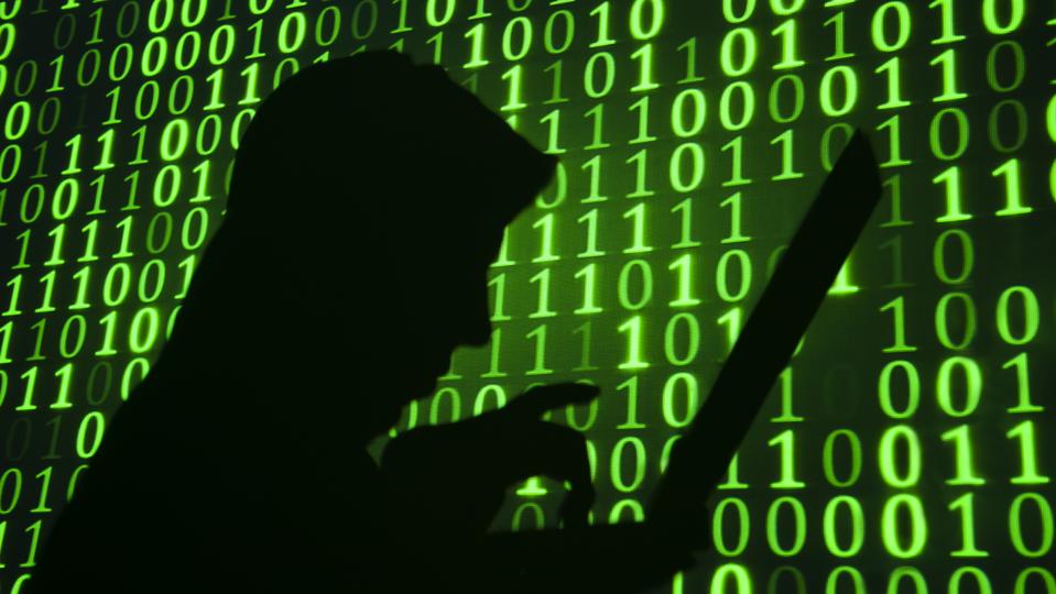 Computer hacker silhouette with green binary code background