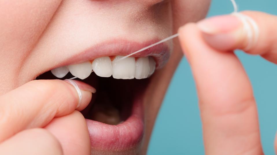 side view woman face smiling with dental floss.