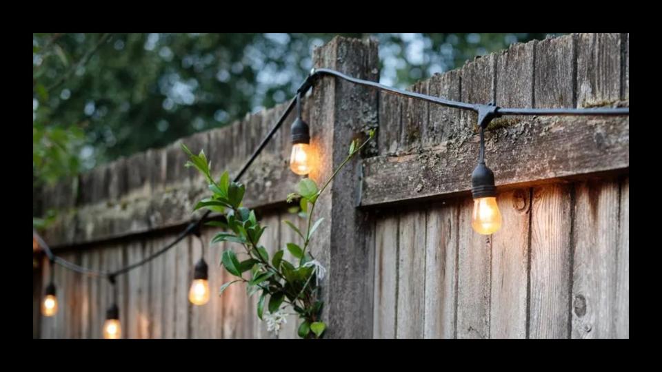 Black Edison string lights hanging from an outdoor fence