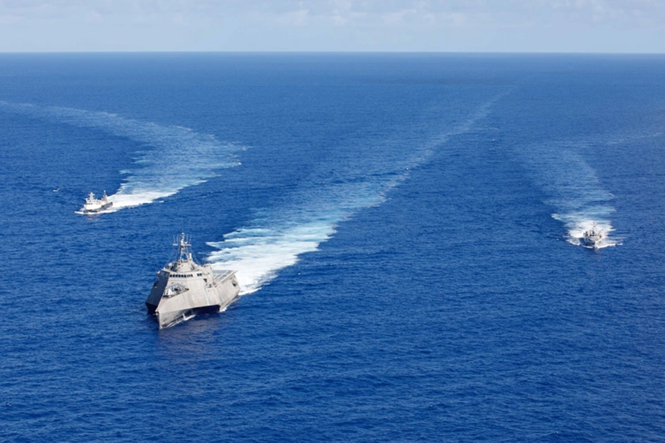 A U.S. Navy Littoral Combat Ship cruises with autonomous prototype vessels.