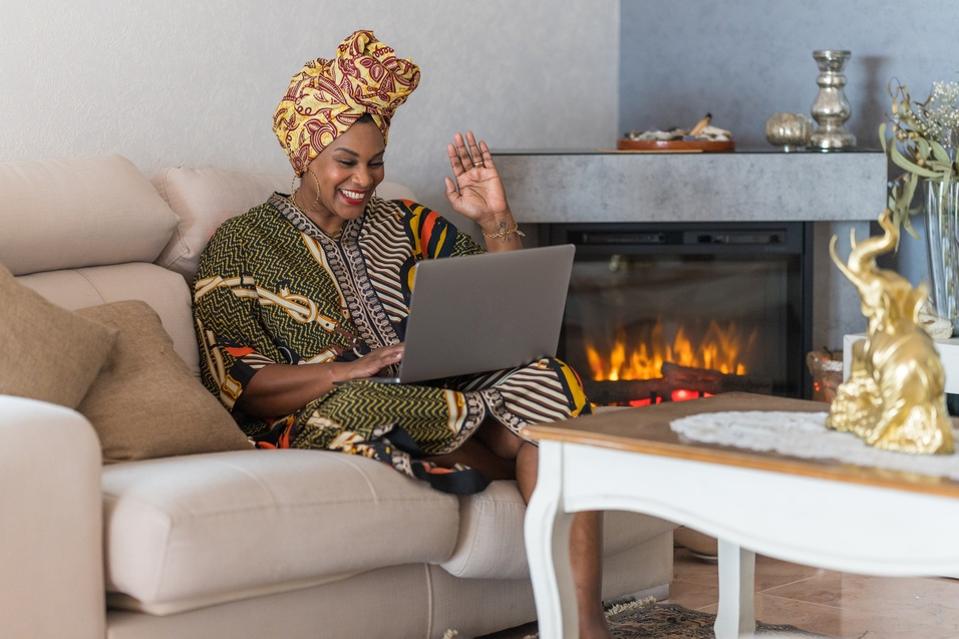 Black entreprenur woman using laptop in wealthy home, in a virtual meeting