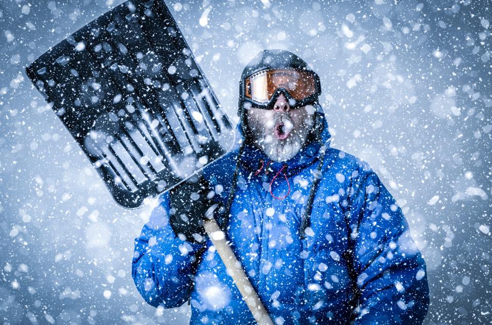 Man with goggles and shovel during snowstorm