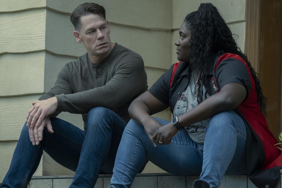 a man and a woman sitting on a porch step and talking to each other