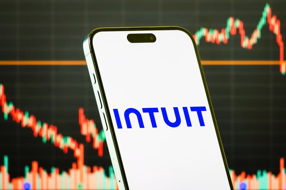 Intuit Inc. logo displayed on smartphone with stock market chart background