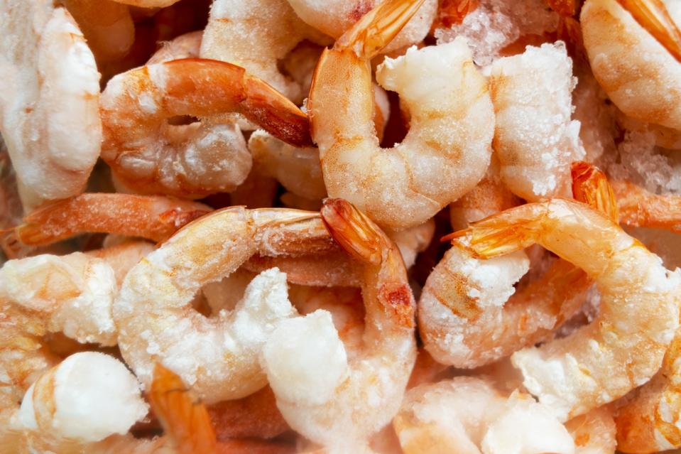 Raw frozen and peeled shrimp background. Pile of frozen shrimps .Close-up of frozen shrimps. A lot of royal shrimp macro shot
