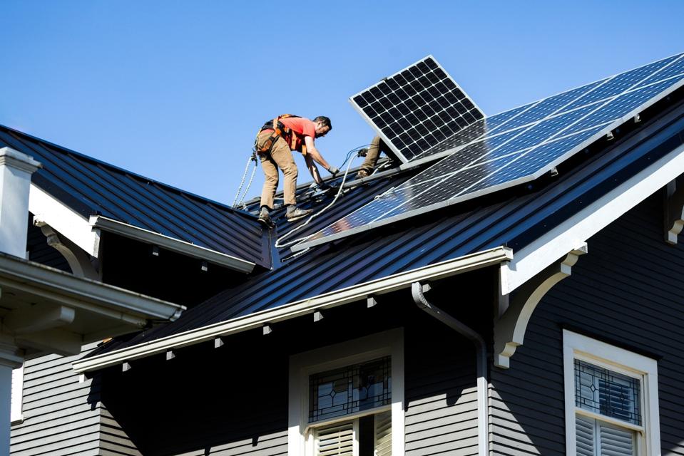 A professional solar panel crew installs panels on the roof of a house in Washington state, USA.