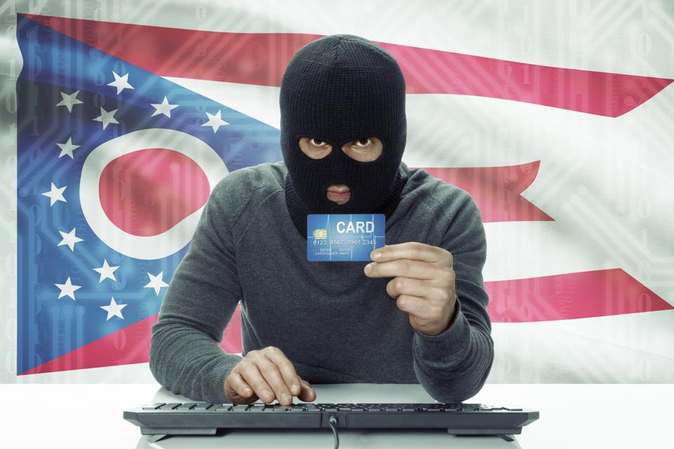 Hacker with Ohio flag on background holding credit card 