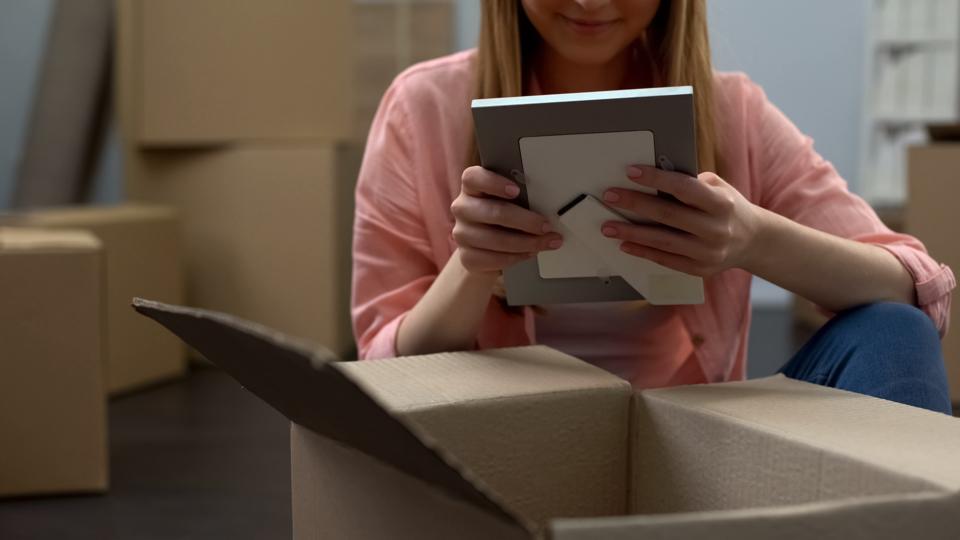 Student unpacking things in dormitory, looking at family photos