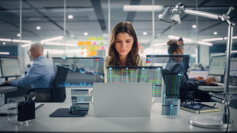 Young happy businessman using laptop computer in modern office with colleagues. We have a stylish and beautiful financial advisor. I visualized the VFX Hologram Editing Stock Exchange interface and opened the chart.