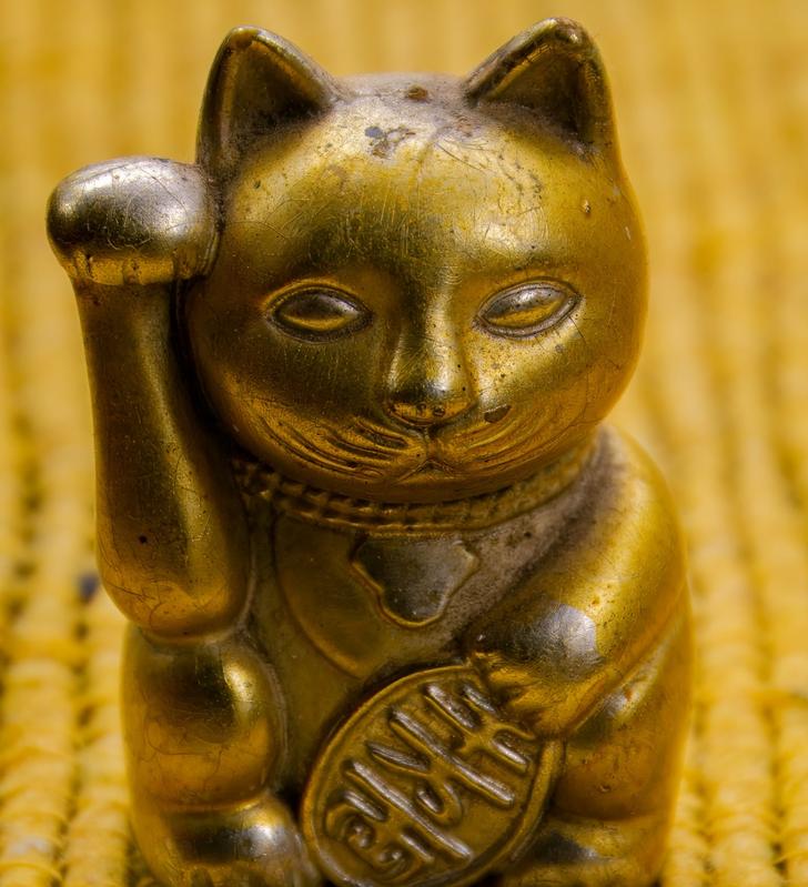 Small beckoning cat toys in yellow background, close-up