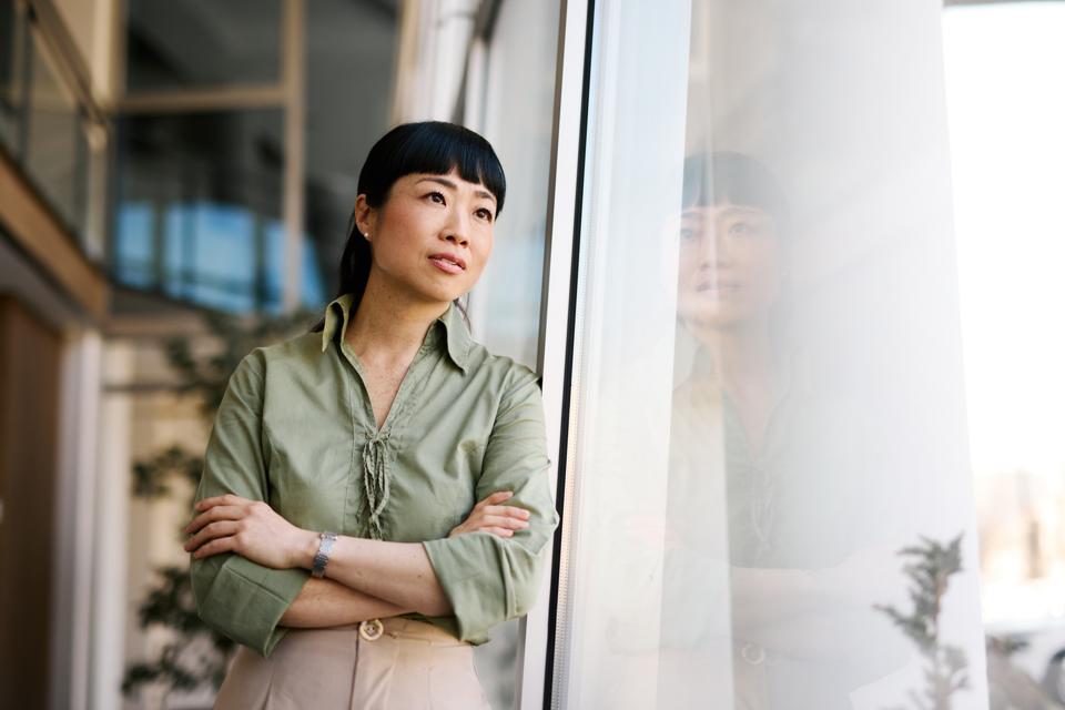 Businesswoman Leaning Against Window in Modern Office