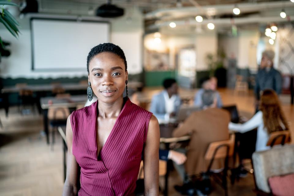 Portrait of a young businesswoman with coworkers on the background