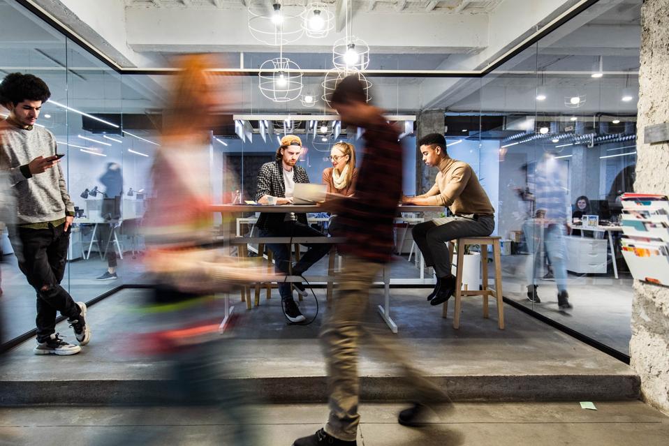 Young creative people working in the office among people in blurred motion.