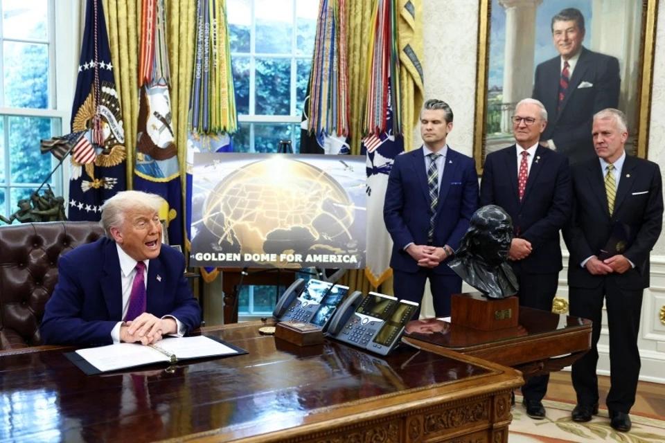 Trump speaks in Oval Office with a Golden Dome poster displayed behind him.