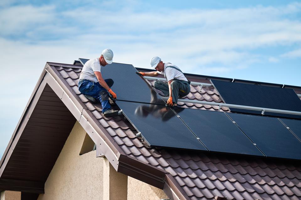 Workers installing photovoltaic solar module outdoors. 