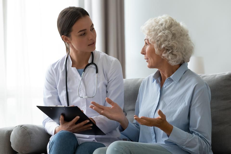 Senior woman telling about health complaints to young nurse