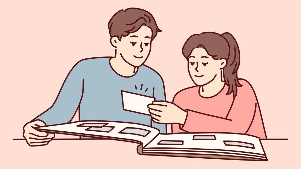 Happy couple man and woman looking at family photo album with pictures sits at table. Vector image