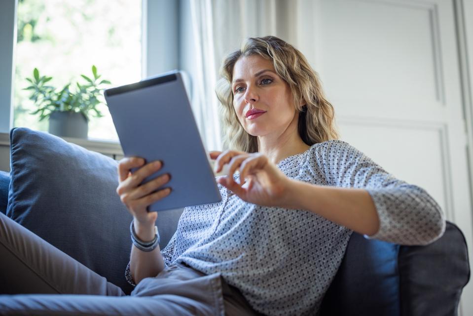 Female investor holds tablet at home.