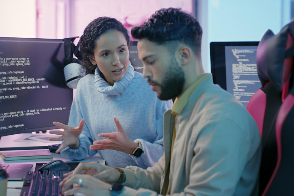 Computer, woman programmer and man training for coding, cyber security or software on computer. Female IT specialist, male coder or talking to connect internet, information update and cloud computing