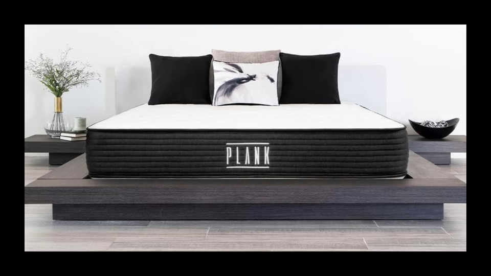 The Plank Firm mattress on a wooden bed frame.