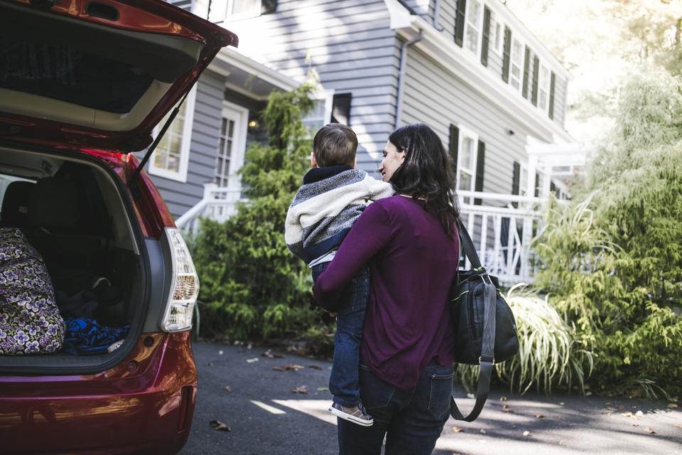 Woman and son standing by car in driveway