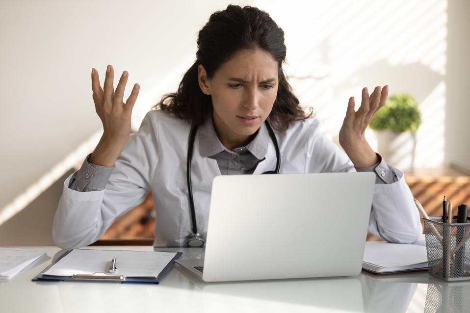 Angry female doctor have problems working on computer