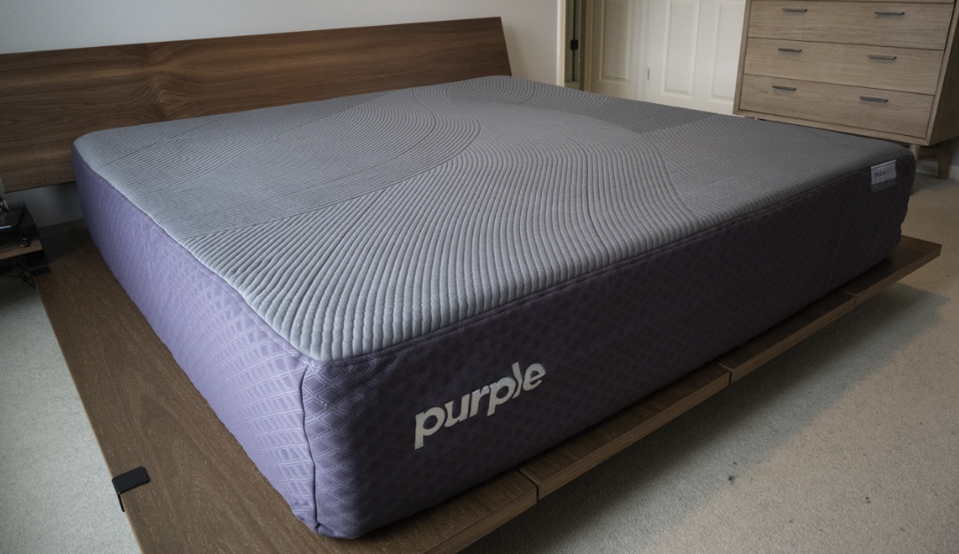 The Purple RestorePremier Hybrid on a wooden bed frame.
