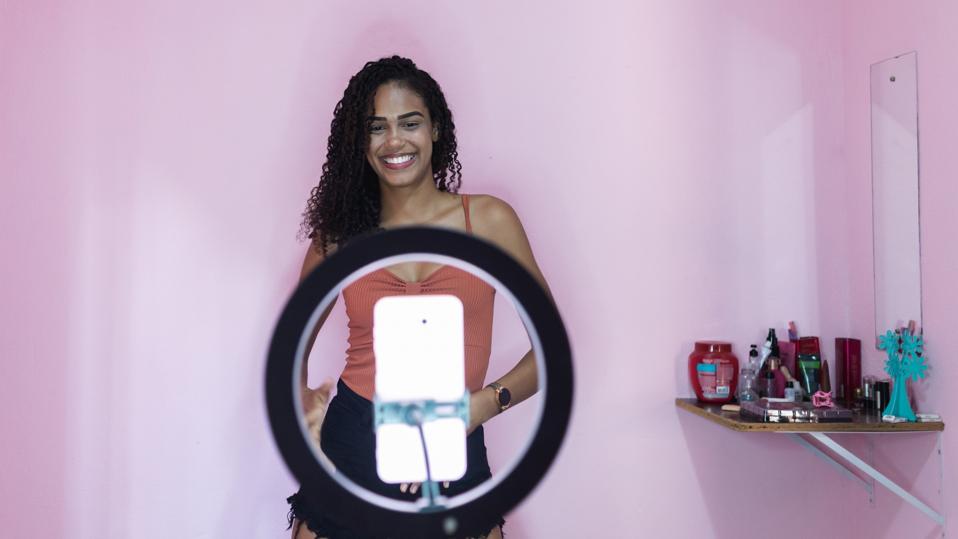 Black young woman filming herself dancing at home to share on social media