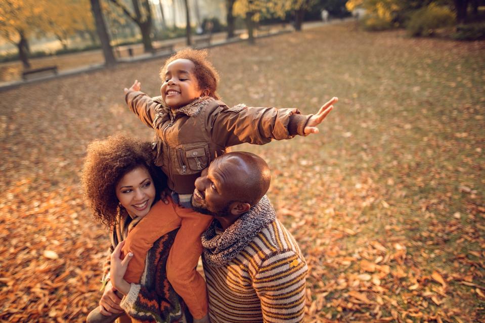 Happy African American family having fun in the fall.