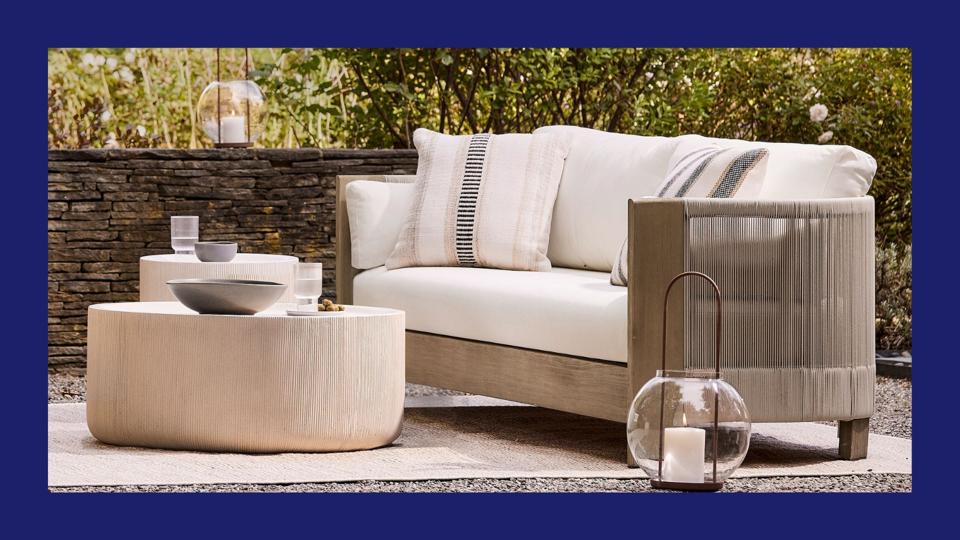 An outdoor sofa and table on a backyard patio.