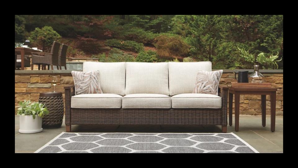 Lifestyle picture of the Highland Dunes Estill Patio Sofa in a backyard.