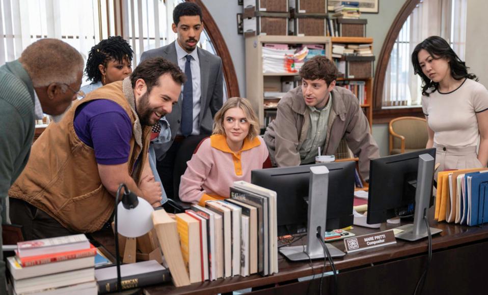 The cast of Peacock's "The Paper" huddled around a newsroom desk