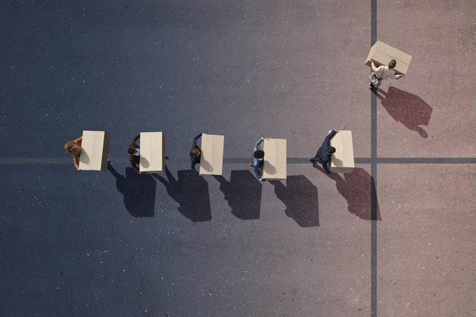 Businesspeople with moving boxes walking in line. One person turning left.