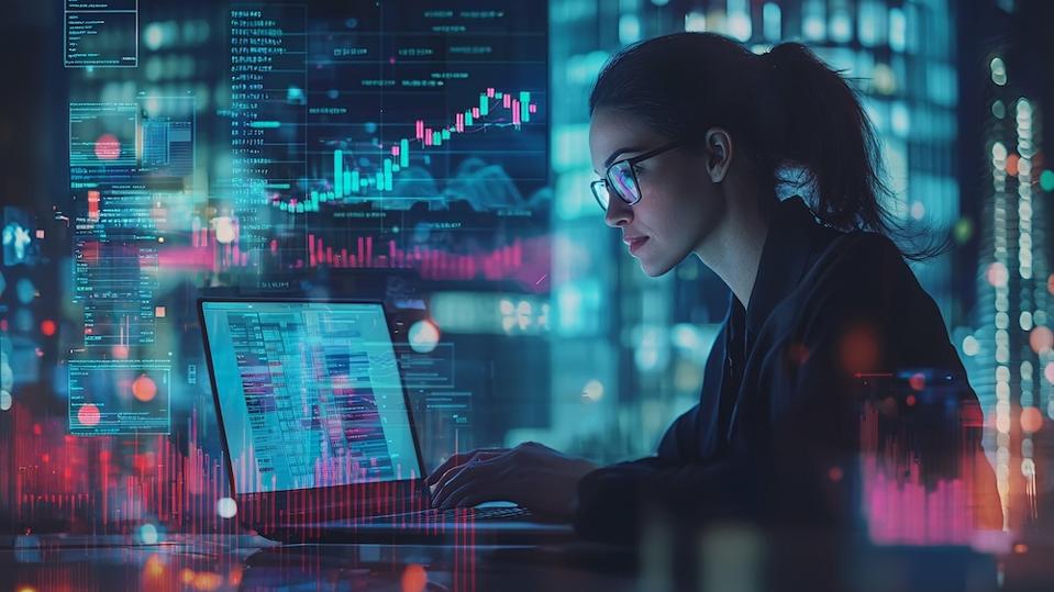 A businesswoman reviews data on her laptop amid charts and graphs in a modern office.