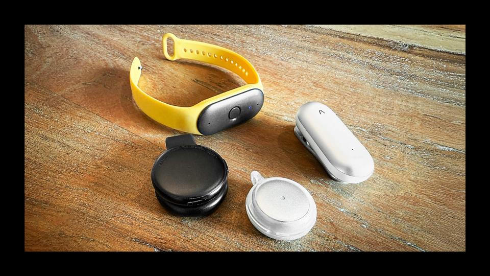 AI wearables devices, Bee, Plaud NotePin, Omi and Limitless, sitting on a tabletop.