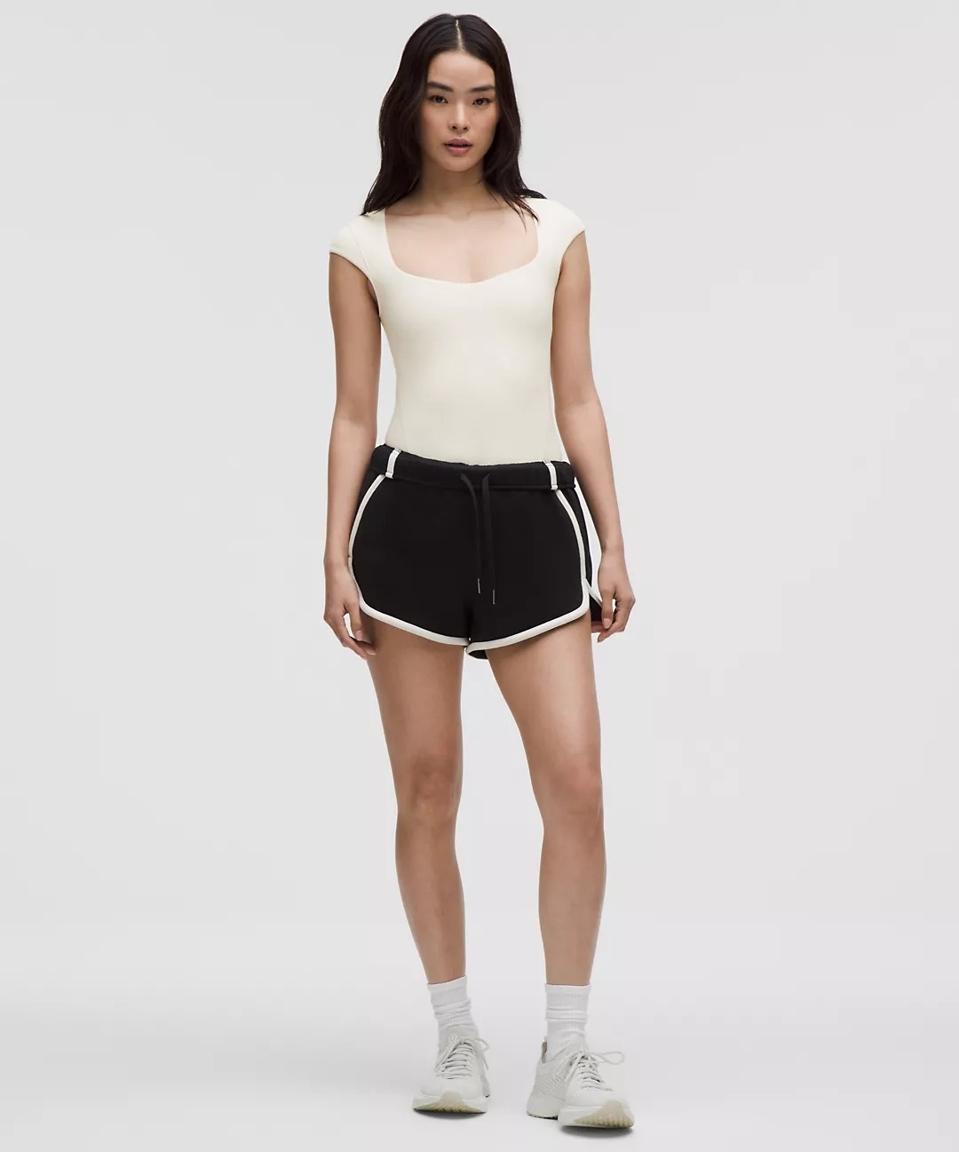 women wearing a white Lululemon Wundermost Ultra-Soft Nulu Thong Bodysuit and black shorts