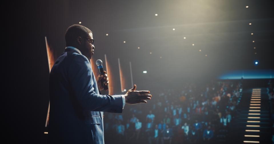 African Businessman Speaking at a Global Economic Strategies at International Business Conference. Public Speaker Sharing Professional Knowledge and Leadership Insights. Shot from Behind