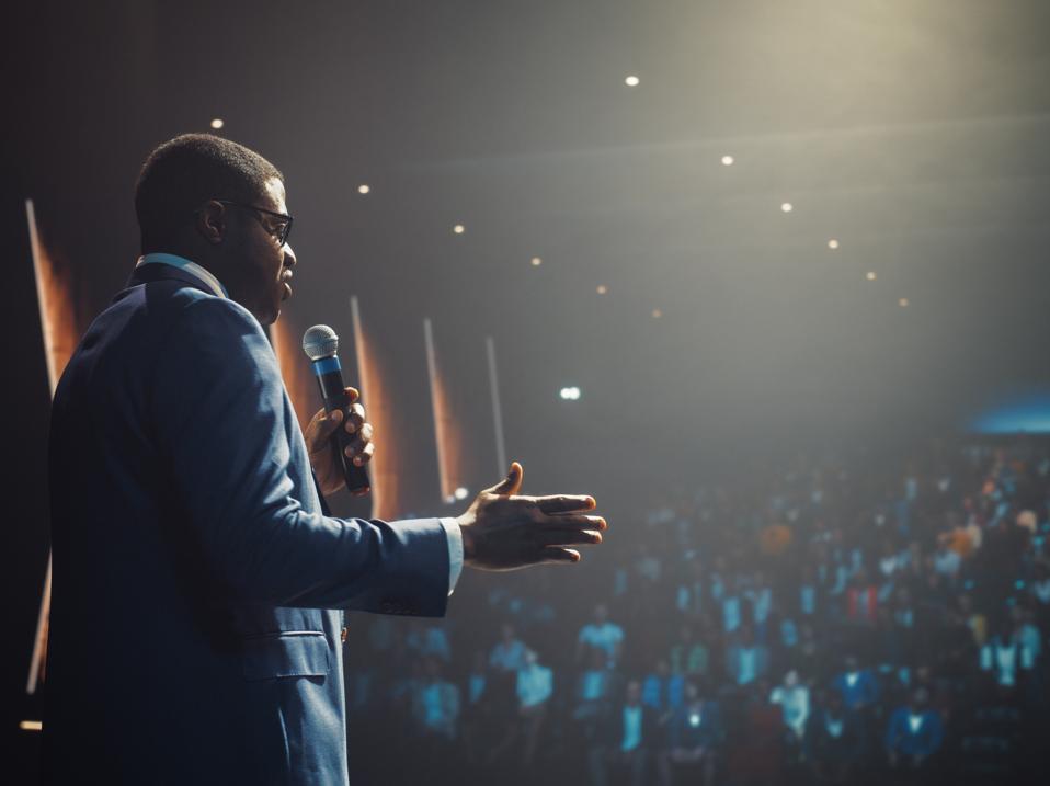 African Businessman Speaking at a Global Economic Strategies at International Business Conference. Public Speaker Sharing Professional Knowledge and Leadership Insights. Shot from Behind