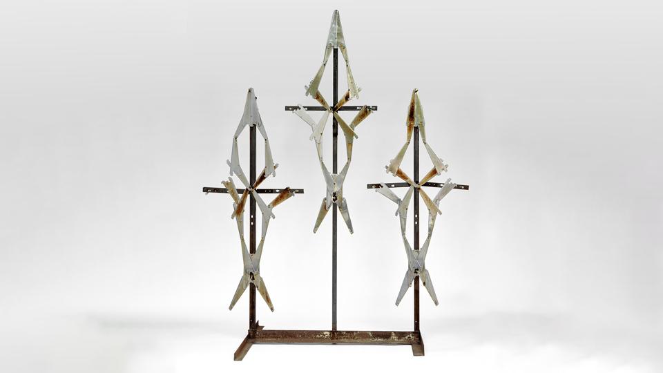 Industrial steel brackets are pierced by garage nails in a reimagining of Jesus crucified