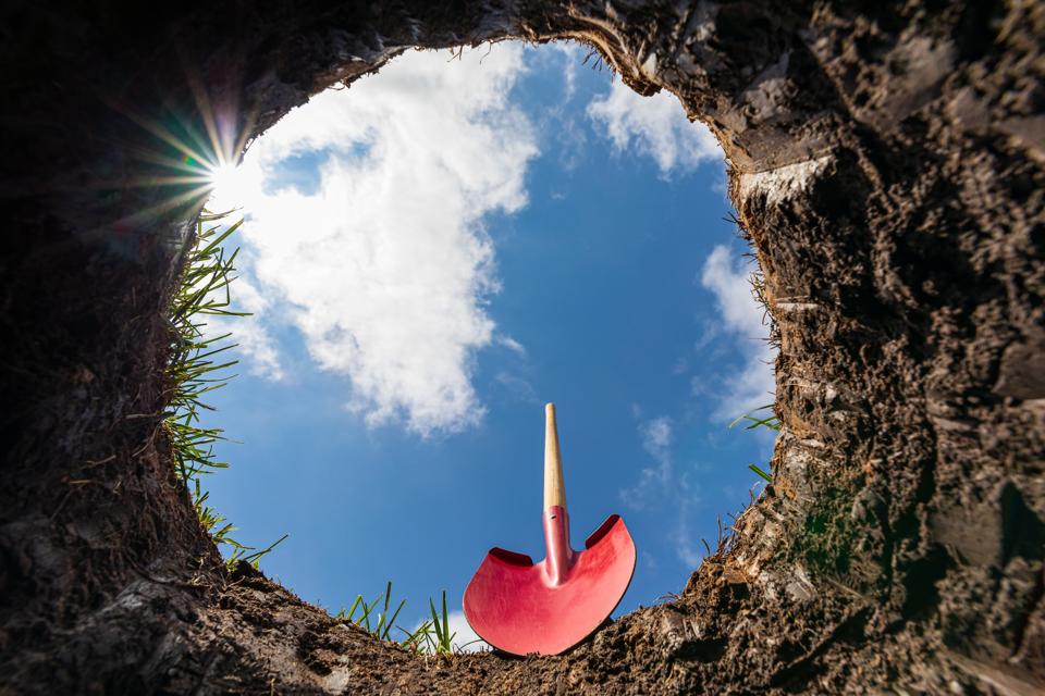 Looking up from hole in yard with shovel. Buried underground utilities, digging a hole and gardening concept