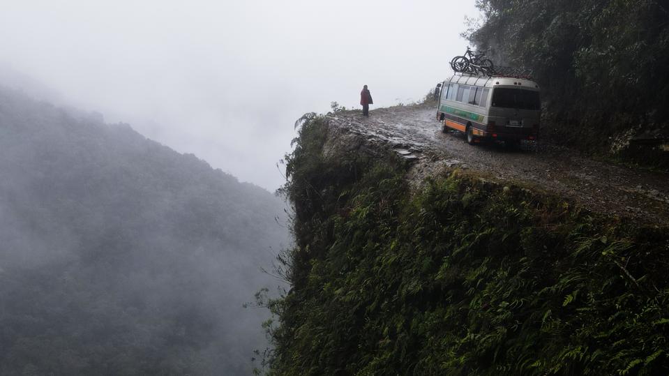 A bus travels along a cliff-side road.